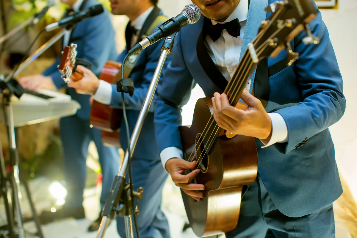 Musicians in suits playing guitar and singing at a wedding
